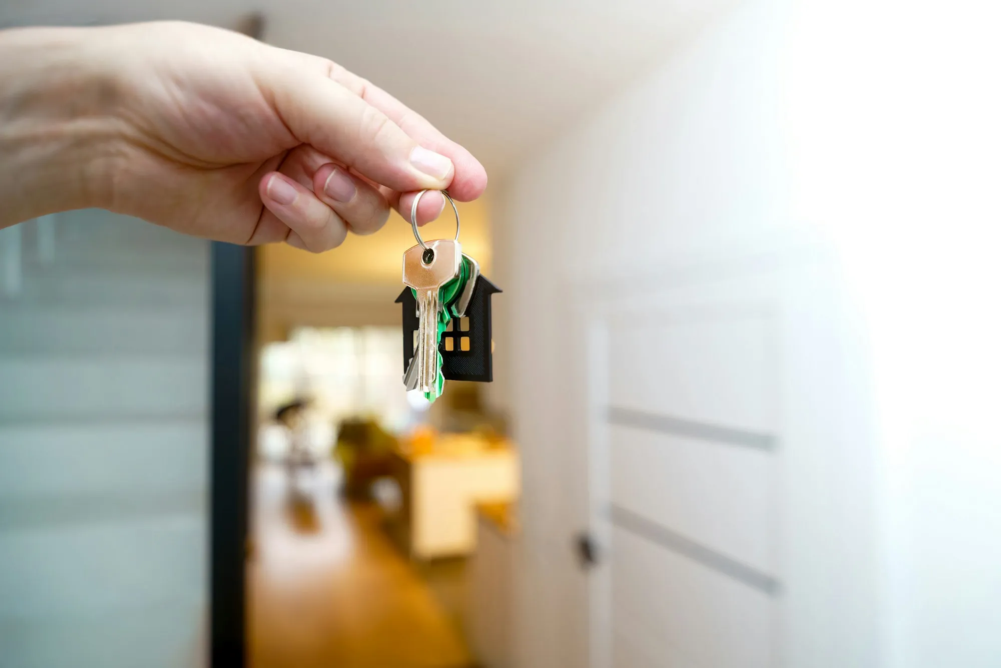 Hand holding up a house key in a doorway