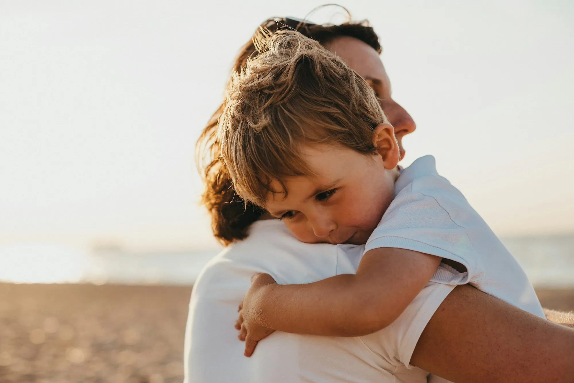 Child hugging a parent tightly at sunset
