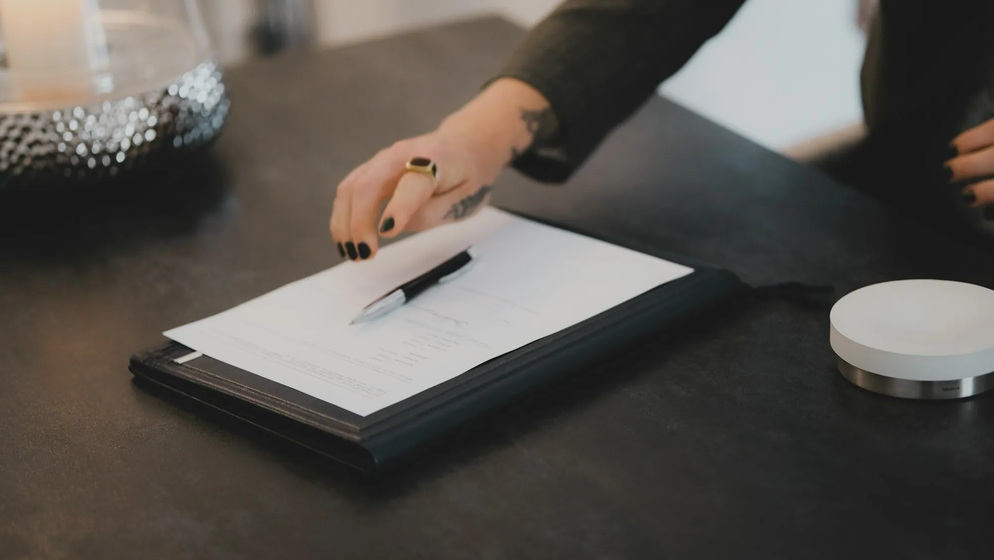 Hand resting a pen on a clipboard